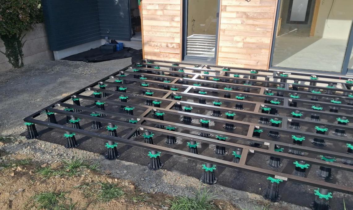 Lambourdes aluminium Réversil posées sur plots réglables devant une maison à bardage bois